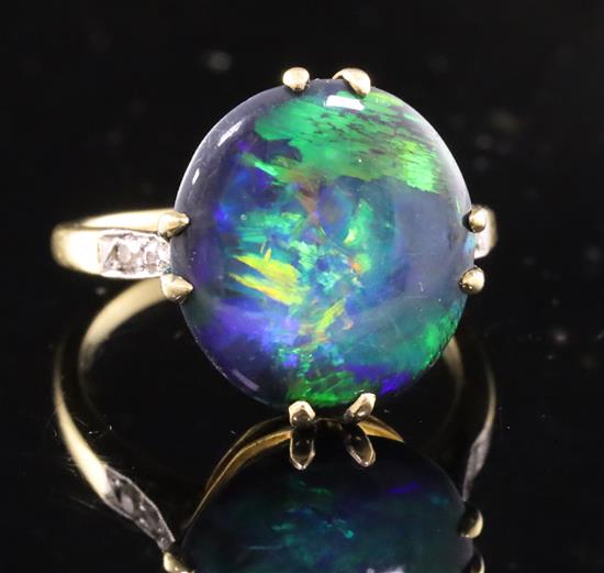 A 1920s 18ct gold, platinum and oval black opal dress ring with diamond set shoulders, size M.